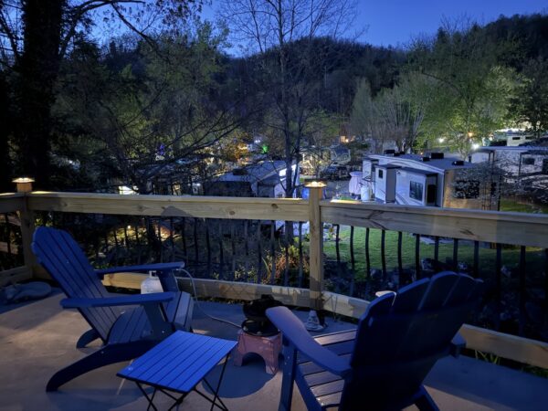 Creekside lot at dusk with adirondack chairs on patio by fence overlooking creek and resort Outdoor Resorts and Gatlinburg