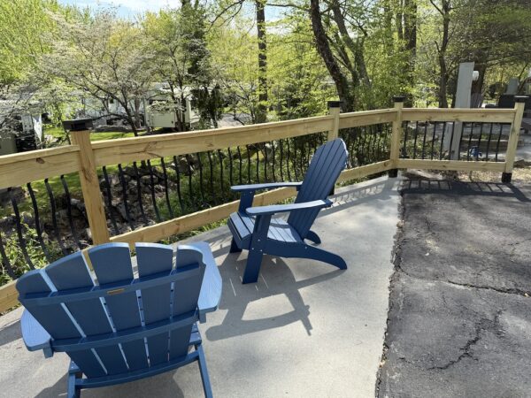Blue adirondack chairs on patio by fence overlooking creek on creekside site Outdoor Resorts at Gatlinburg