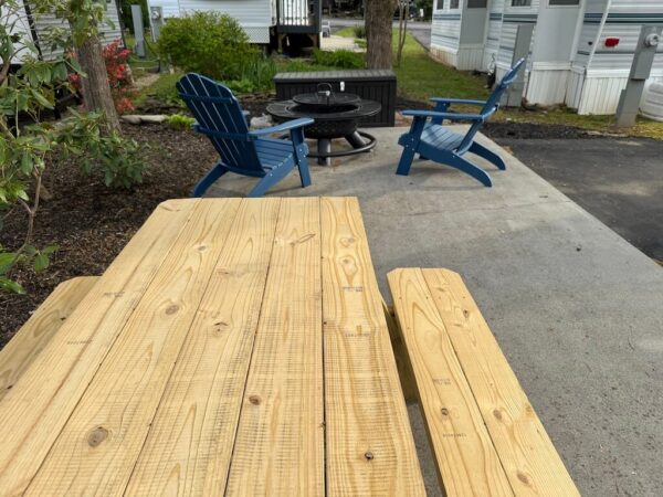 View of picnic table and firepit with adirondack chairs on Mountain Vibes site Outdoor Resorts at Gatlinburg